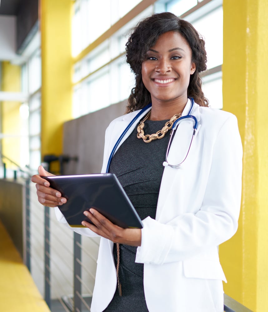 Portrait of a female doctor holding her patient chart on digital tablet in bright modern hospital-1 Portrait of a female doctor holding her patient chart on digital tablet in bright modern hospital-1
